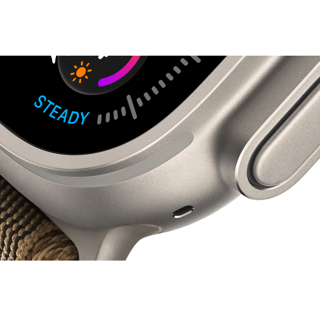 Close-up of a smartwatch with a silver metallic case, a textured brown woven strap, and a black display showing the word 'STEADY' and colorful interface elements.